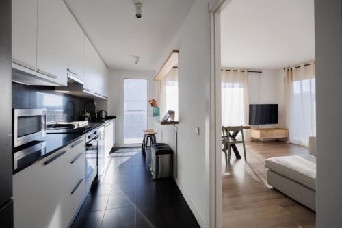 een keuken met witte apparatuur en een woonkamer bij Gran Apartmento Playa Badalona in Badalona