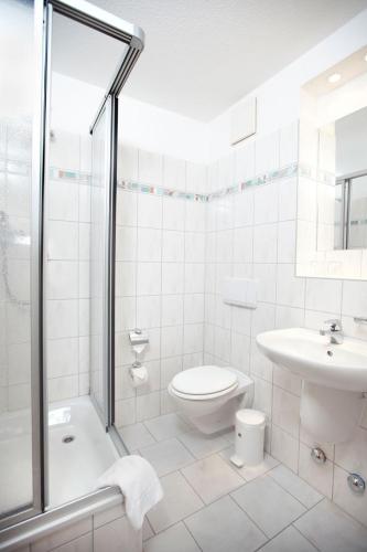 a white bathroom with a toilet and a sink at Meeressterne Hotel Idyll Am Wolgastsee in Korswandt