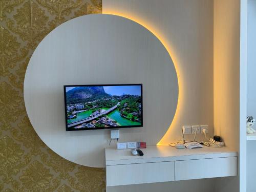 a tv on a wall with a round mirror at Wiwi Formosa Residence Nagoya Batam in Nagoya