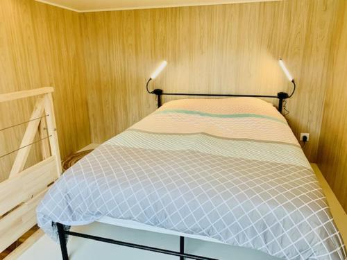 Ce lit se trouve dans un dortoir doté d'un mur en bois. dans l'établissement Tiny House à 10min du Mont Saint Michel, à Pontorson
