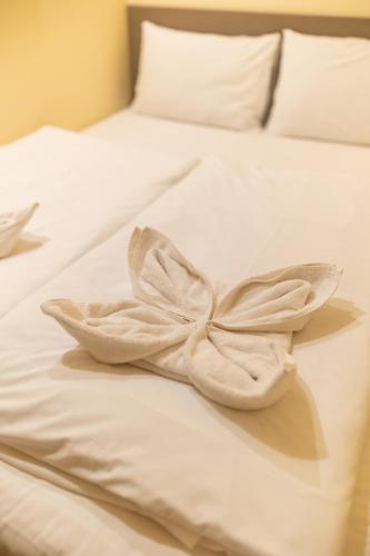 a white bed with a flower on it at LelleMarine by BLTN Apartmanok Balatonlelle in Balatonlelle