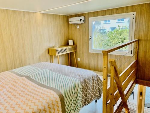 niewielka sypialnia z łóżkiem i oknem w obiekcie Tiny House à 10min du Mont Saint Michel w mieście Pontorson
