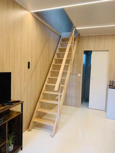 - un escalier en bois dans une chambre avec une télévision dans l'établissement Tiny House à 10min du Mont Saint Michel, à Pontorson