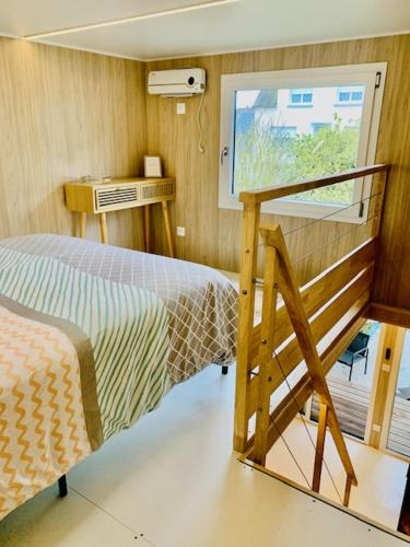 ein kleines Schlafzimmer mit einem Bett und einem Fenster in der Unterkunft Tiny House à 10min du Mont Saint Michel in Pontorson