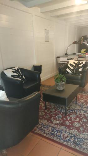 a living room with two black chairs and a table at Duna Parque Beach Club - Duna Parque Resorts & Hotels in Vila Nova de Milfontes