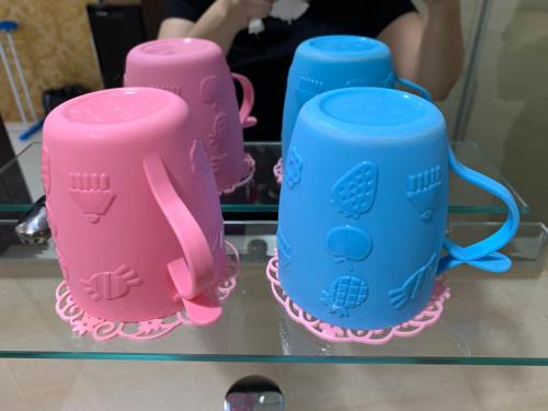 three pink and blue cups on a glass shelf at Wiwi Formosa Residence Nagoya Batam in Nagoya