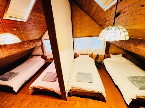 Dos camas en una habitación con paredes de madera. en Yufuin Log House no Yado Tom Sawyer, en Yufu