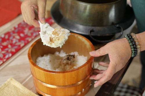 a person putting a piece of food into a bowl at 棚田ハウス in Murai