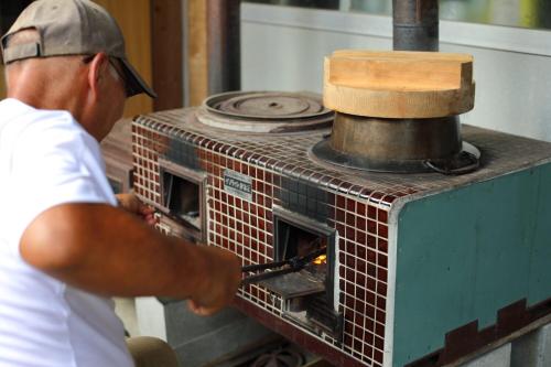 a man putting something into a brick oven at 棚田ハウス in Murai