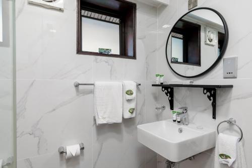 a white bathroom with a sink and a mirror at Mweya Safari Lodge in Katwe