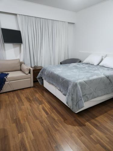 a bedroom with a bed and a couch at Hotel Slavieiro Moema Suite Prime Familia in Sao Paulo