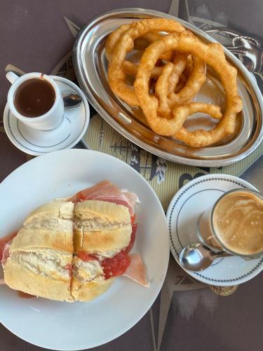 ein Sandwich, Zwiebelringe und eine Tasse Kaffee in der Unterkunft Larios Premium Apartments in Málaga