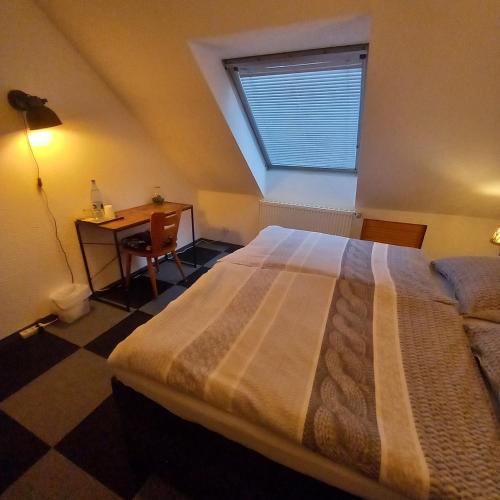 Schlafzimmer mit einem Bett, einem Schreibtisch und einem Fenster in der Unterkunft Zur alten Metzgerei in Alf