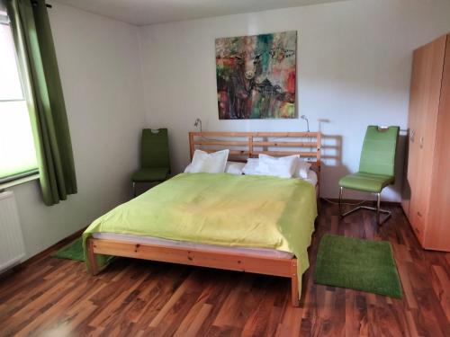 ラーデボイルにあるFerienwohnung Am Hausberg in Radebeulのベッドルーム1室(ベッド1台、緑の椅子2脚付)