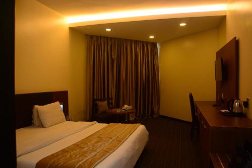 哈科特港的住宿－Hotel Presidential，配有一张床和一张书桌的酒店客房