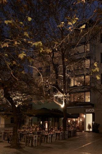 a building with tables and a tree in front of it at Athens Woo Suites in Athens