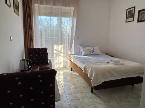 1 dormitorio con 1 cama, 1 silla y 1 ventana en Pansion Vila Vanda Vukovar, en Vukovar