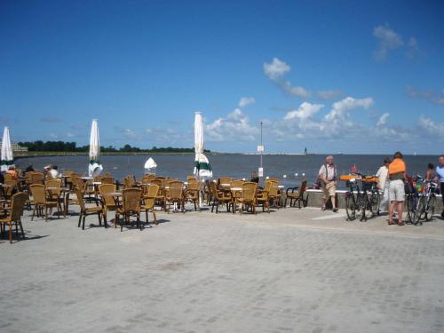 a group of people standing around tables and chairs on the beach at Haus Sonnensegler - Ferienwohnung in Cuxhaven