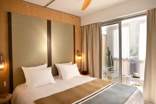 1 dormitorio con 1 cama grande con almohadas blancas en MOB HOTEL Cannes, en Cannes