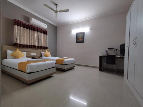 a bedroom with two beds and a desk with a laptop at Luxor Park Service Apartment in Hyderabad