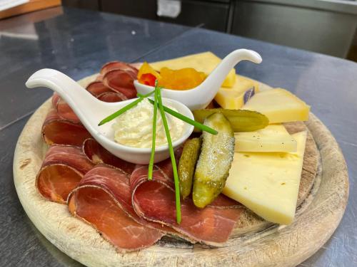 a plate of food with meat and cheese and dips at Ski Lodge Pampeago in Tesero