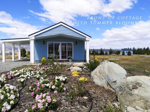 a small blue house with flowers in a yard at Kahurangi Cottage Twizel in Twizel