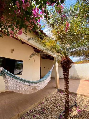 a hammock in front of a house with a palm tree at Elegância e Espaço. Casa Grande Individual in Palmas