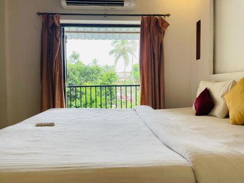 a bedroom with a large bed with a window at The merit resort in Arpora