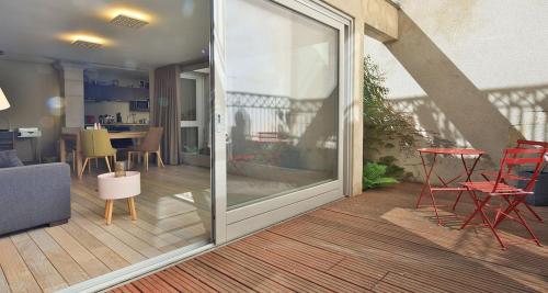 - une porte coulissante en verre sur une terrasse avec une table et des chaises dans l'établissement L'Aparté, à Nancy