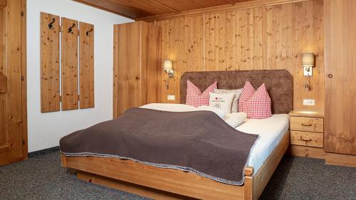 a bedroom with a large bed with red and white pillows at Appartements Alpenrose in Längenfeld