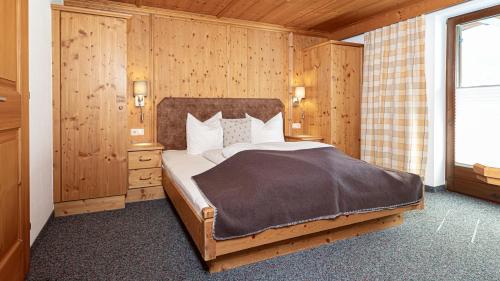 een slaapkamer met een groot bed in een houten kamer bij Appartements Alpenrose in Längenfeld