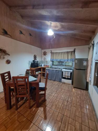 eine Küche mit einem Tisch und Stühlen sowie eine Küche mit einem Herd in der Unterkunft Cabaña Martita in Pucón