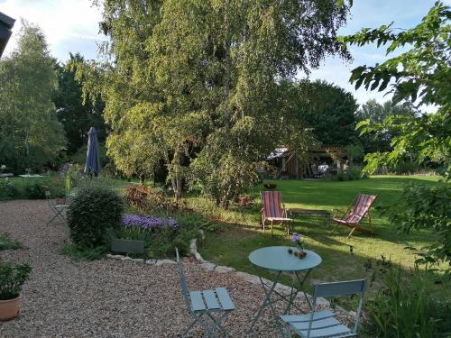 un giardino con due sedie, un tavolo e un albero di La Robinière Maison d'Hôtes a Mont-près-Chambord