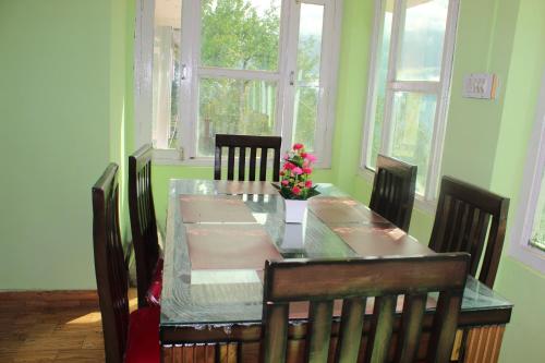 une salle à manger avec une table, des chaises et des fleurs. dans l'établissement THE BLISS HOME STAY, à Kalpa