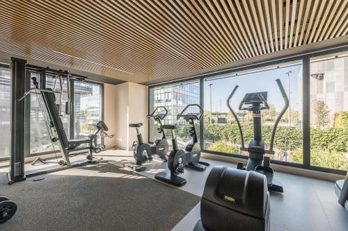 un gimnasio con cintas de correr y elípticas en una habitación con ventanas en Apartamento Torre Australis en Madrid