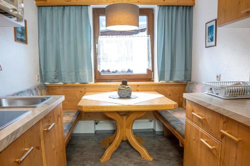 a kitchen with a wooden table and a window at Appartements Alpenrose in Längenfeld
