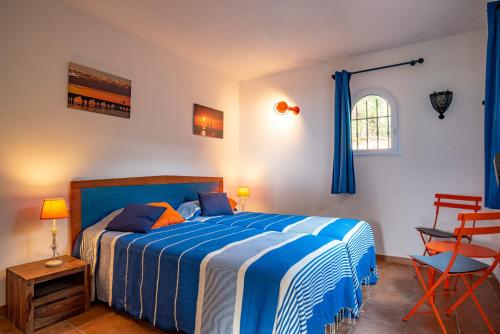 a bedroom with a blue and white bed and a chair at Résidence Les Hameaux de Santa Giulia in Porto-Vecchio