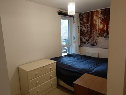 a bedroom with a bed and a dresser and a window at Stylish 2BD near Gatwick Airport in Crawley in Crawley