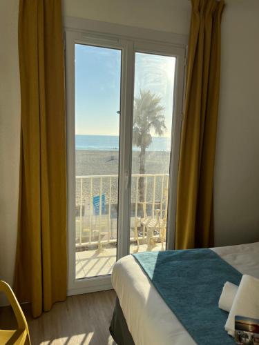 a bedroom with a window with a view of the beach at Hotel Saint Georges, Face à la mer in Canet-en-Roussillon