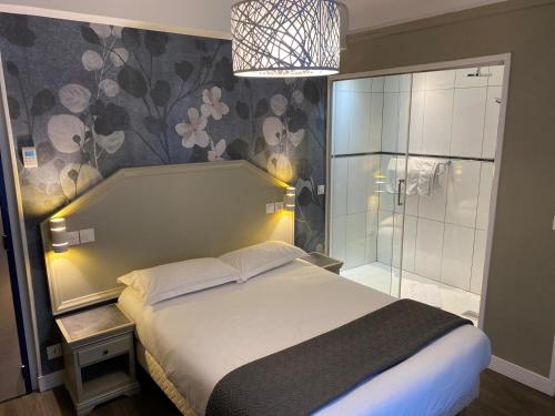 1 dormitorio con 1 cama y ducha acristalada en Hôtel Ambassadeur, en París