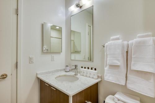 uma casa de banho branca com um lavatório e um espelho em Downtown studio w gym wd nr waterfront BOS-985 em Boston