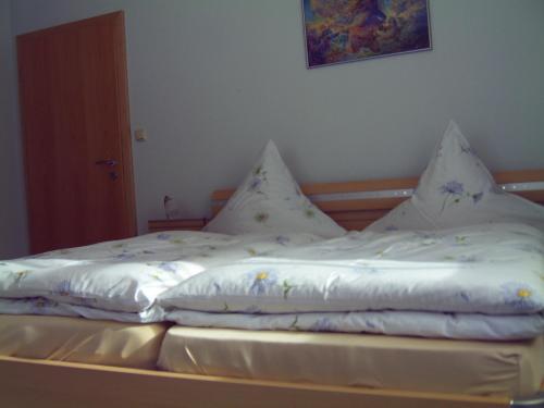Una cama con sábanas blancas y almohadas. en Ferienwohnung Reisinger, en Arnbruck