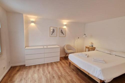 a white bedroom with a bed and a chair at Cathedral Apartment in Barcelona