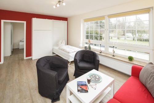 a living room with a couch and chairs and a bed at Marbijes Appartementhaus in Cuxhaven