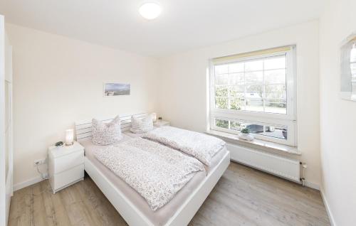a white bedroom with a bed and a window at Marbijes Appartementhaus in Cuxhaven