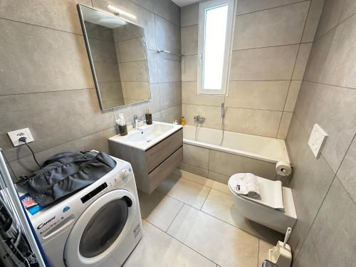 a bathroom with a washing machine and a sink at Grand appartement proche de Délemont avec terrasse by Stay Swiss 