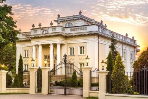 una casa blanca con una puerta y una valla en Pałacyk Otrębusy Business & Spa, en Otrębusy