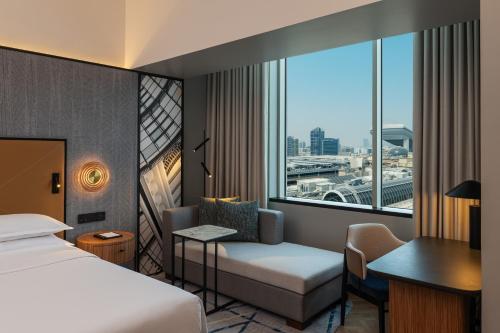 Sheraton Mall of the Emirates Hotel, Dubai في دبي: غرفه فندقيه بسرير ومكتب ونافذه