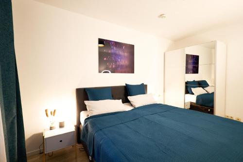 a bedroom with a blue bed and a mirror at Gemütliche 2Zi. Wohnung in Seligenstadt