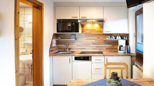 a small kitchen with white cabinets and a sink at Appartements Alpenrose in Längenfeld